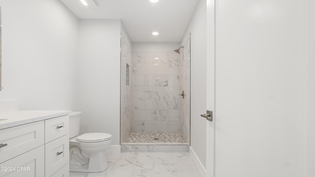 bathroom with vanity, toilet, and tiled shower