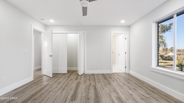 unfurnished bedroom with ceiling fan, a closet, light hardwood / wood-style flooring, and multiple windows