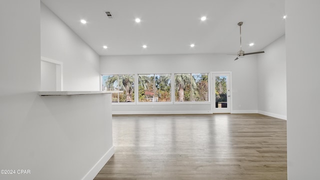 unfurnished room with wood-type flooring, a towering ceiling, and ceiling fan