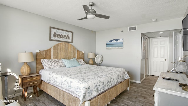 bedroom with dark hardwood / wood-style flooring, ceiling fan, and a textured ceiling