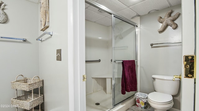 bathroom featuring toilet, a drop ceiling, and a shower with shower door