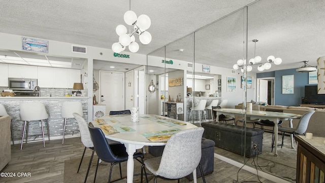 dining space with dark hardwood / wood-style flooring, a textured ceiling, and an inviting chandelier