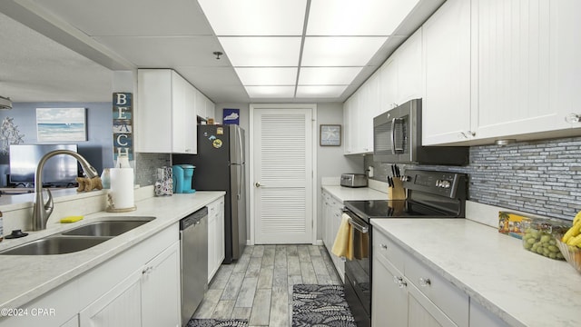 kitchen featuring white cabinetry, sink, decorative backsplash, stainless steel appliances, and light hardwood / wood-style flooring