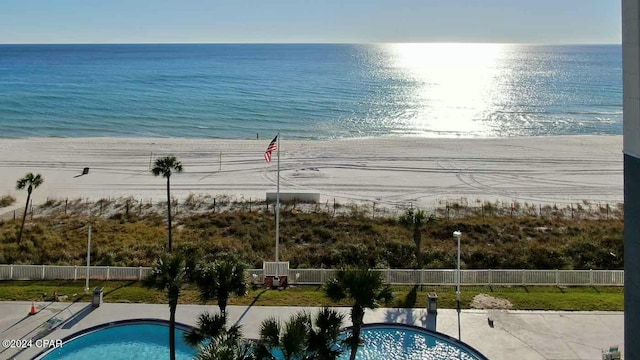 view of pool featuring a water view and a beach view