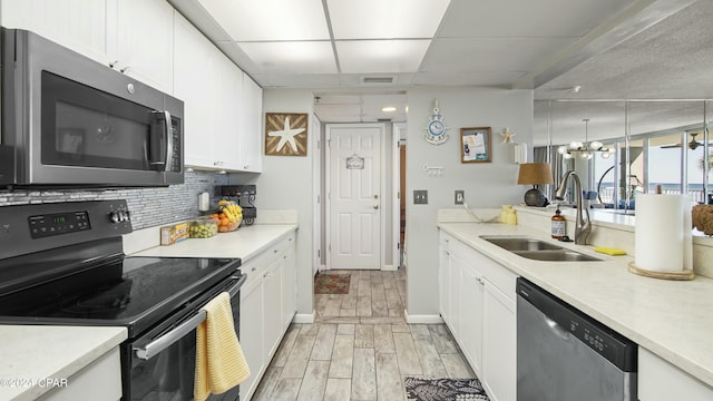 kitchen featuring tasteful backsplash, sink, white cabinets, stainless steel appliances, and a drop ceiling