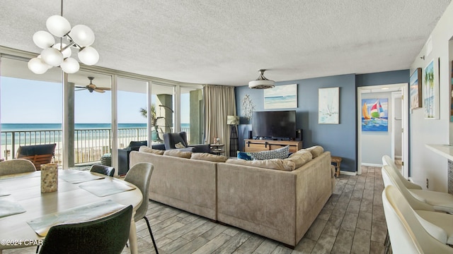 living room featuring ceiling fan, wood-type flooring, floor to ceiling windows, and a textured ceiling