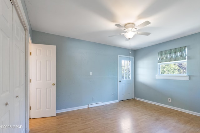 empty room featuring ceiling fan, light wood-type flooring, and baseboard heating