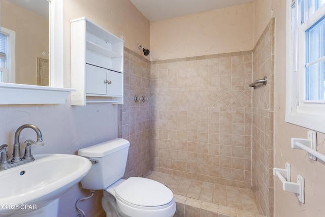 bathroom featuring toilet, sink, and tiled shower