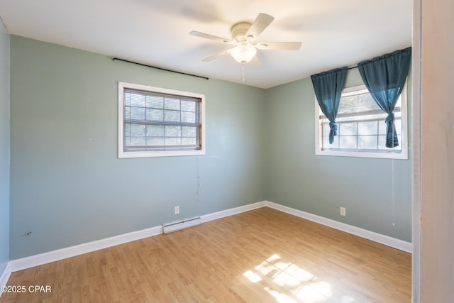 spare room featuring a baseboard heating unit, hardwood / wood-style flooring, a healthy amount of sunlight, and ceiling fan