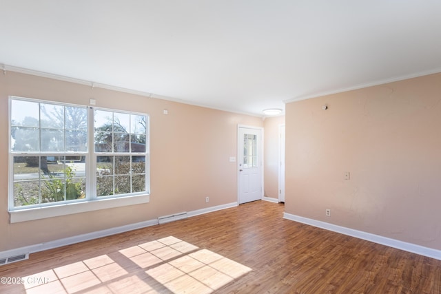 spare room featuring crown molding, light wood-type flooring, and a wealth of natural light