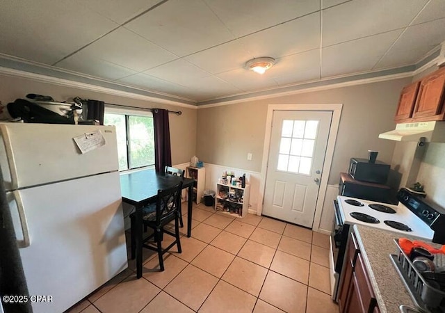 kitchen featuring electric stove, light tile patterned floors, ornamental molding, and white fridge