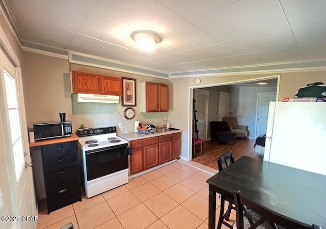 kitchen featuring crown molding, light tile patterned floors, and white appliances