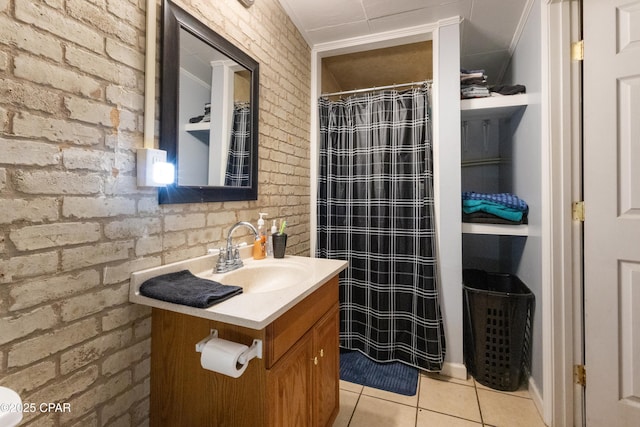 bathroom featuring vanity, tile patterned floors, and brick wall