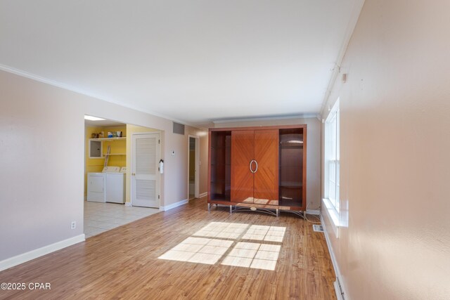 empty room featuring ornamental molding, washer and clothes dryer, and light wood-type flooring