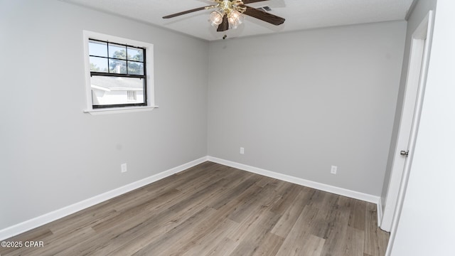 spare room featuring a ceiling fan, baseboards, and wood finished floors