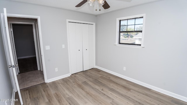 unfurnished bedroom with light wood-style floors, a ceiling fan, baseboards, and a closet