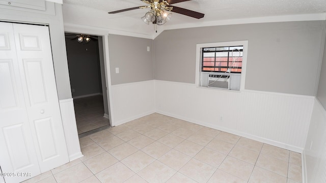 empty room with light tile patterned floors, ceiling fan, wainscoting, and cooling unit