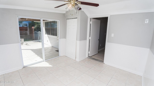 spare room with a wainscoted wall, ceiling fan, and light tile patterned flooring