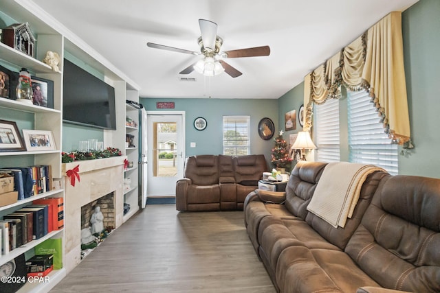 living room with hardwood / wood-style flooring, ceiling fan, and a premium fireplace