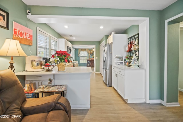 kitchen featuring kitchen peninsula, light hardwood / wood-style flooring, white cabinetry, and stainless steel appliances