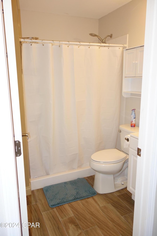 bathroom featuring a shower with curtain, hardwood / wood-style flooring, and toilet