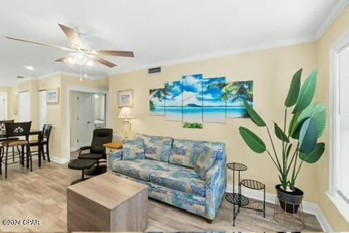 living room with ceiling fan, ornamental molding, a healthy amount of sunlight, and light wood-type flooring