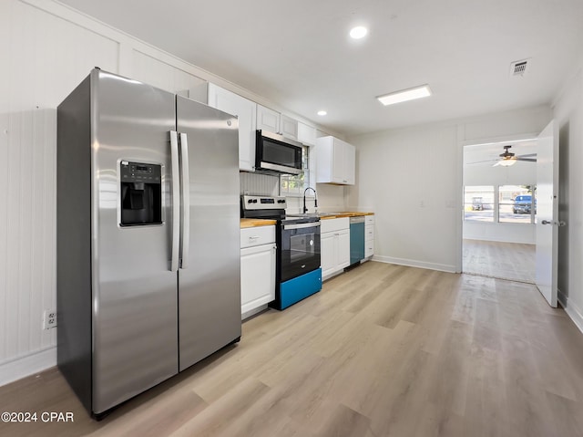 kitchen with white cabinets, light hardwood / wood-style floors, stainless steel appliances, and a wealth of natural light