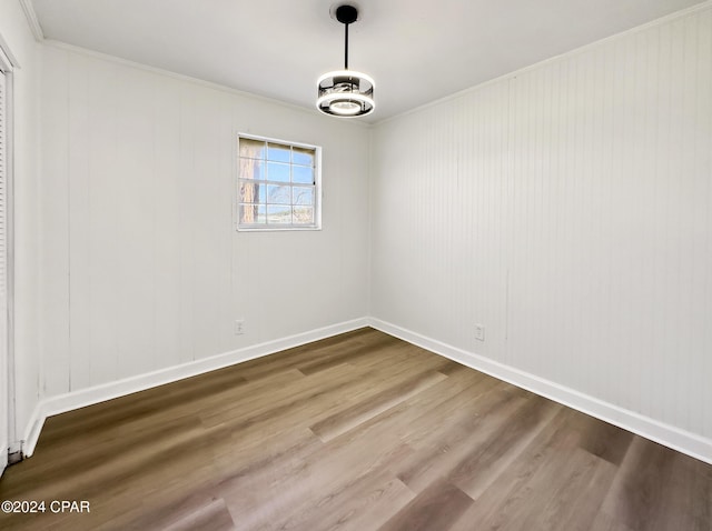 unfurnished room with hardwood / wood-style floors, crown molding, and an inviting chandelier