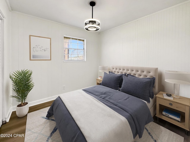 bedroom featuring ornamental molding, a notable chandelier, and hardwood / wood-style flooring