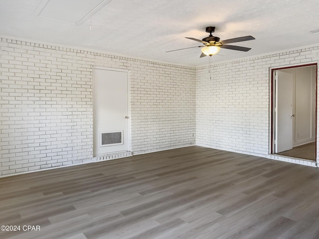 empty room featuring brick wall, a textured ceiling, and hardwood / wood-style flooring