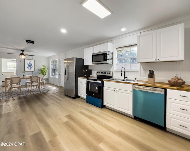 kitchen with wood counters, appliances with stainless steel finishes, white cabinetry, and sink