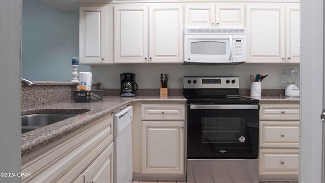 kitchen featuring light stone countertops, sink, white appliances, and white cabinets