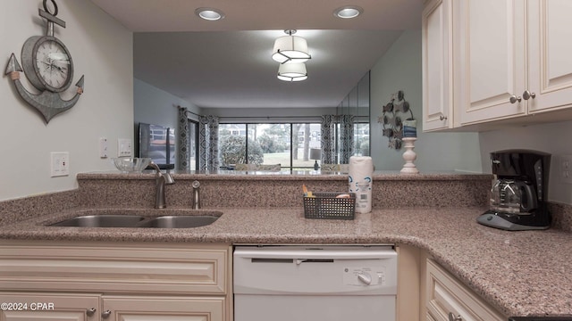 kitchen with light stone counters, sink, and white dishwasher