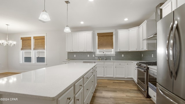 kitchen with stainless steel appliances, a kitchen island, hanging light fixtures, and white cabinetry