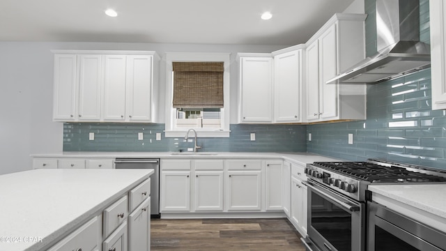 kitchen featuring dark hardwood / wood-style flooring, wall chimney exhaust hood, stainless steel appliances, sink, and white cabinetry