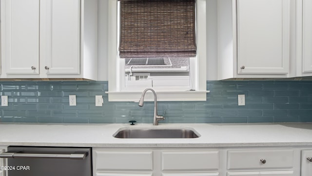 kitchen with decorative backsplash, white cabinetry, sink, and stainless steel dishwasher