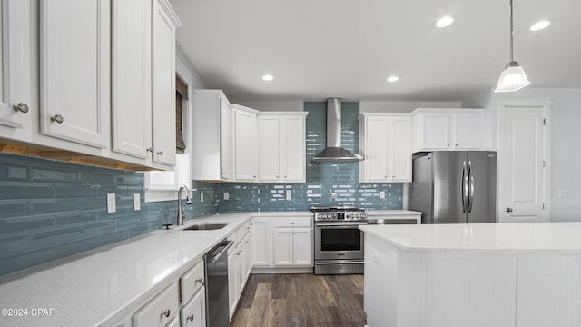 kitchen with white cabinetry, sink, wall chimney exhaust hood, hanging light fixtures, and appliances with stainless steel finishes