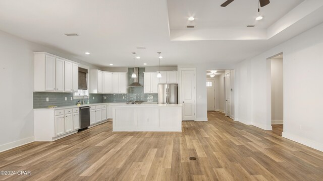 kitchen featuring wall chimney exhaust hood, hanging light fixtures, stainless steel appliances, light hardwood / wood-style floors, and a kitchen island