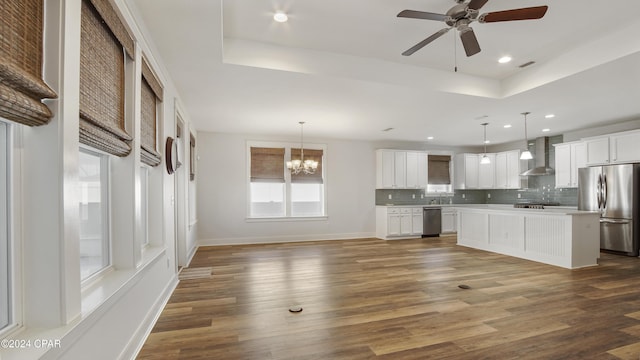 kitchen with wall chimney exhaust hood, a kitchen island, stainless steel appliances, and hanging light fixtures