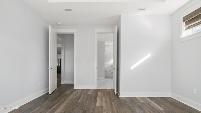 unfurnished bedroom featuring dark hardwood / wood-style flooring and ensuite bath