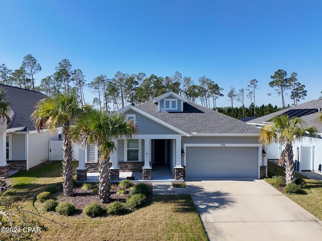 craftsman-style home with covered porch, a garage, and a front yard