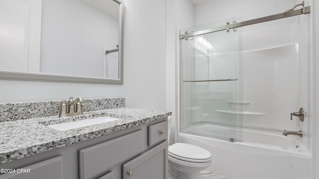 full bathroom with combined bath / shower with glass door, vanity, and toilet