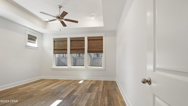 empty room featuring ceiling fan, a raised ceiling, and wood-type flooring