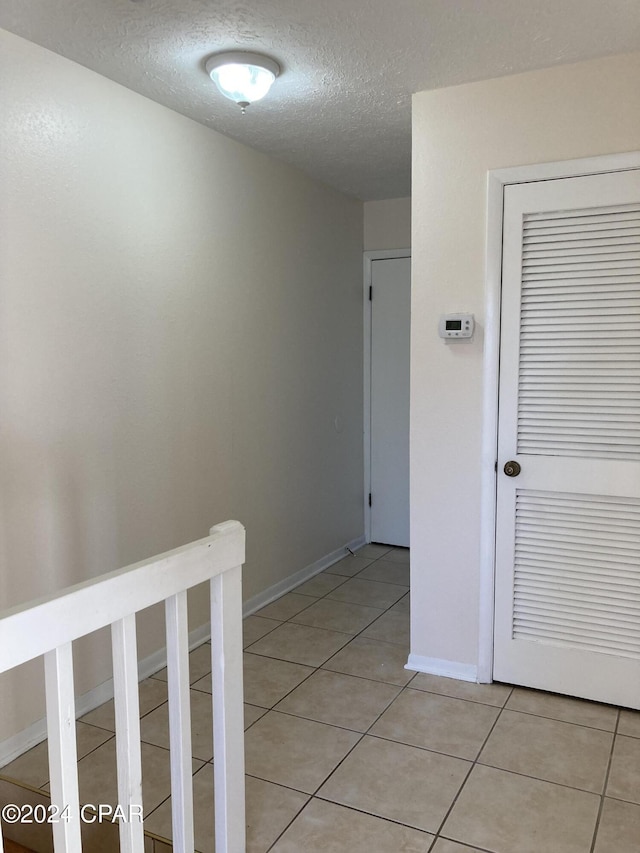 hall featuring light tile patterned floors and a textured ceiling