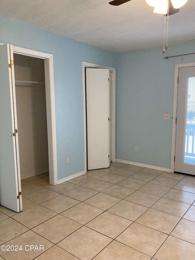 interior space featuring light tile patterned floors, a textured ceiling, a closet, and ceiling fan