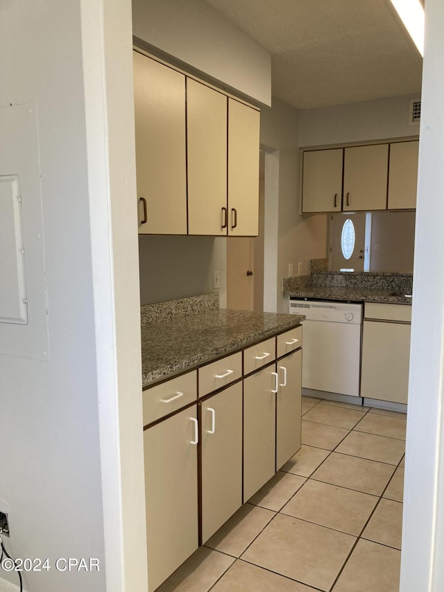 kitchen with dishwasher, light tile patterned floors, electric panel, and dark stone countertops