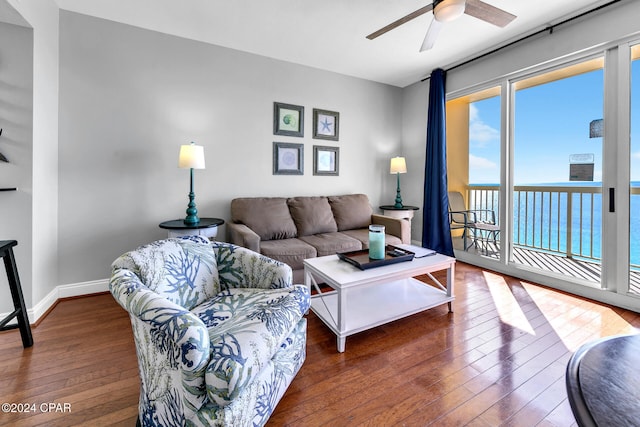 living room with dark hardwood / wood-style floors, ceiling fan, and a water view