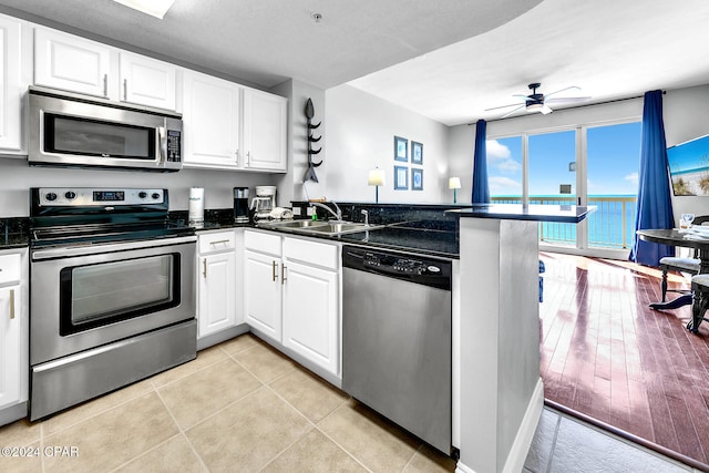 kitchen with white cabinetry, sink, kitchen peninsula, appliances with stainless steel finishes, and light wood-type flooring