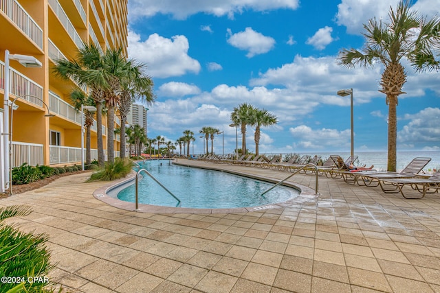 view of swimming pool featuring a patio area and a water view