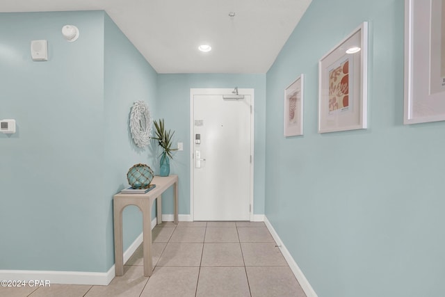 doorway with light tile patterned flooring and baseboards